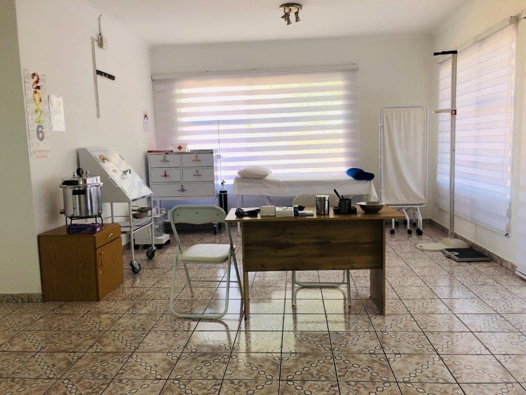 Clinical treatment room with examination bed and steriliser at Elshaddai Health Care Centre